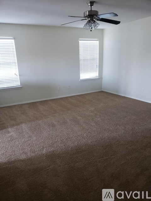 A room with a carpeted floor and a ceiling fan.
