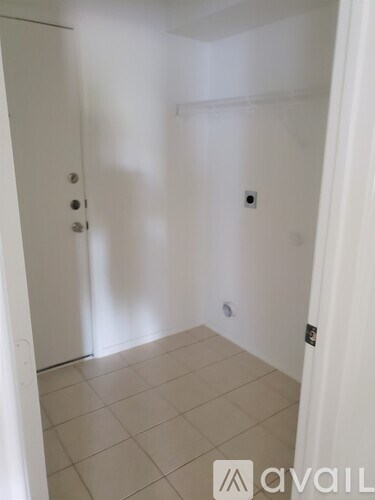 A white door with a silver handle is on the left side of a room with white walls and a tiled floor.
