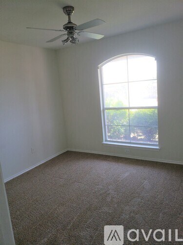 A room with a carpet floor, a ceiling fan, and a window.