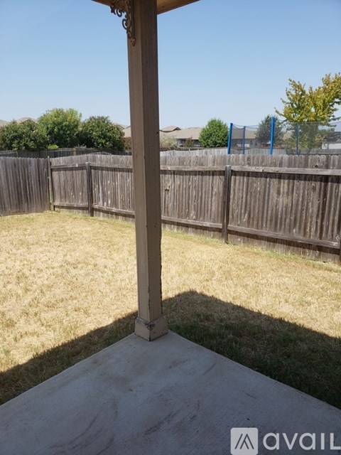 A patio with a concrete floor and a wooden fence.