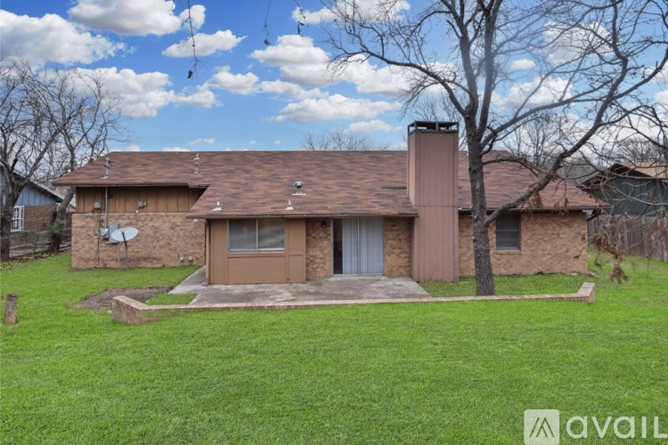 A house with a brown roof and a brown door is surrounded by a gravel area.