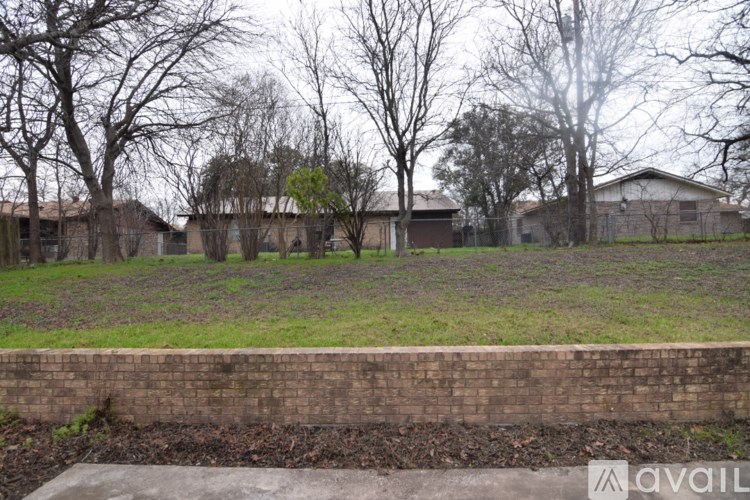 A grassy area with a brick wall and a house in the background.