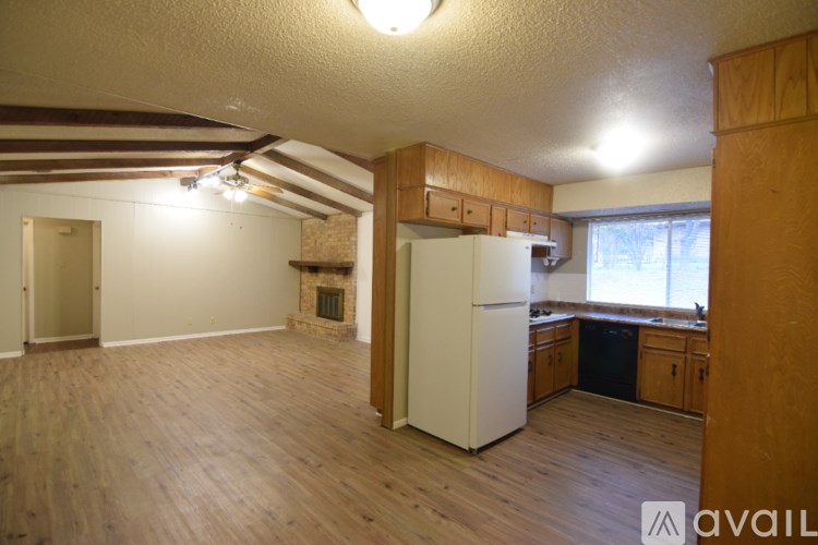 A kitchen with a white fridge and wooden floors.
