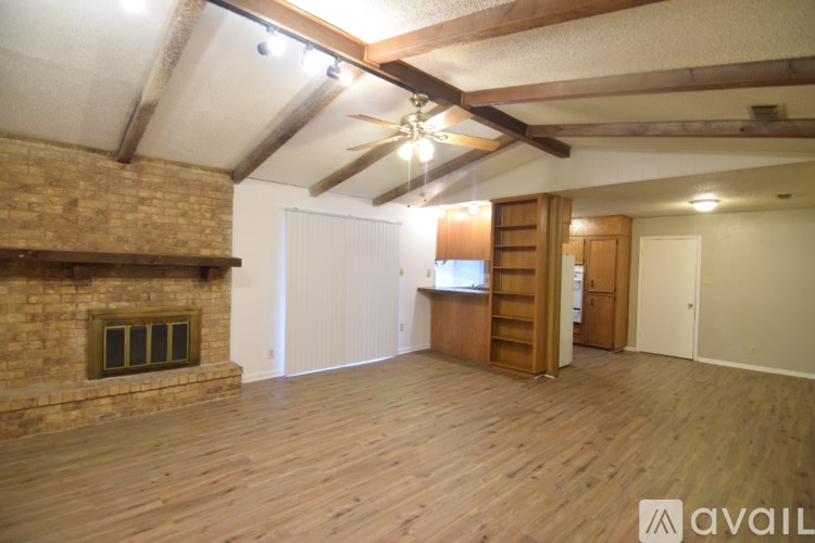 A room with wooden floors and a brick fireplace.