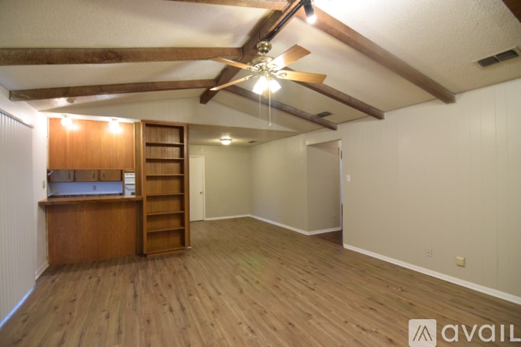 A room with a ceiling fan and wooden flooring.