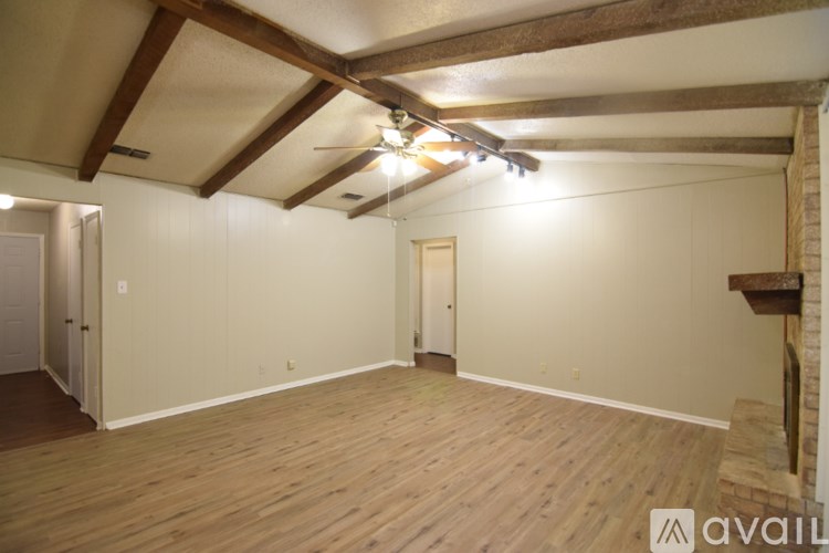 A spacious room with wooden floors and a ceiling fan.