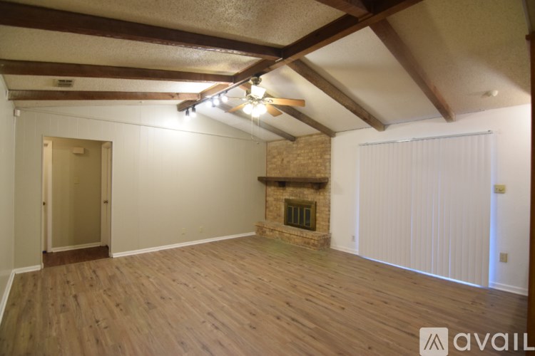 A room with wooden floors and a fireplace with a white wall and a door.
