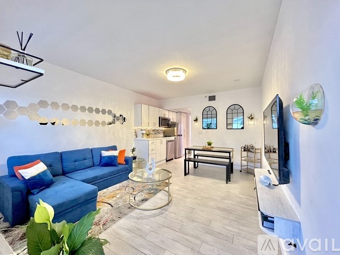 A living room with a blue couch and a glass coffee table.