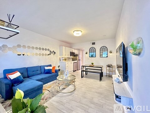 A living room with a blue couch and a glass coffee table.