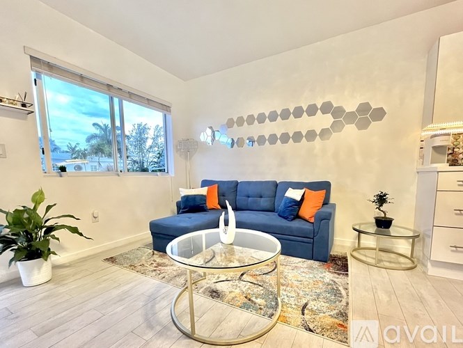 A living room with a blue couch and a glass coffee table.