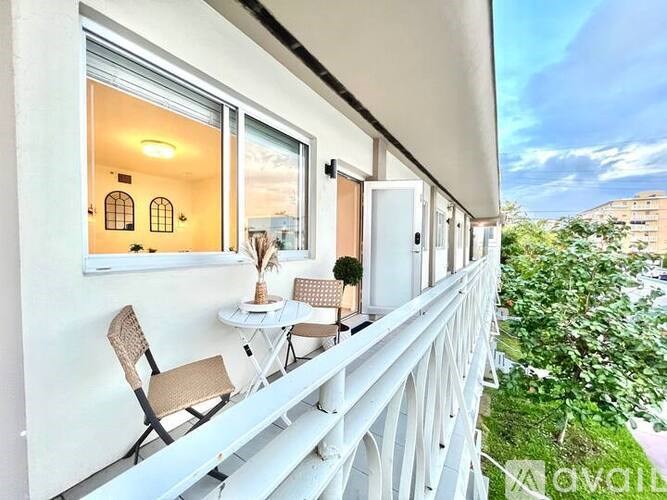 A balcony with a table and chairs overlooks a cityscape.