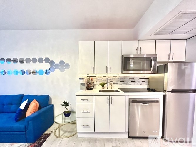 A modern kitchen with a blue couch and white cabinets.