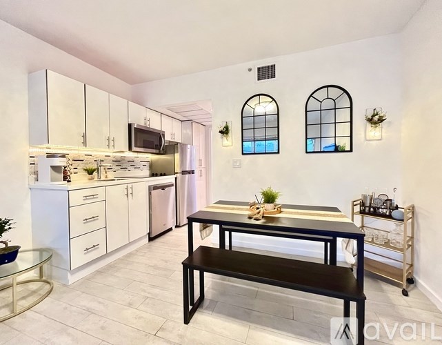 A modern kitchen with a black table and white cabinets.