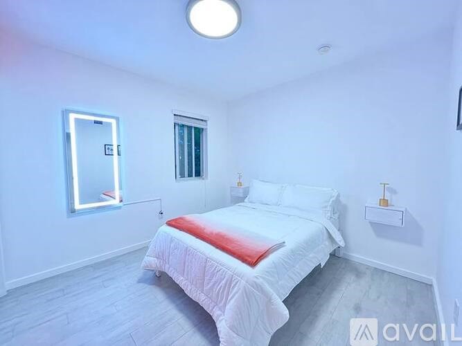 A bedroom with a bed, a window, and a mirror.