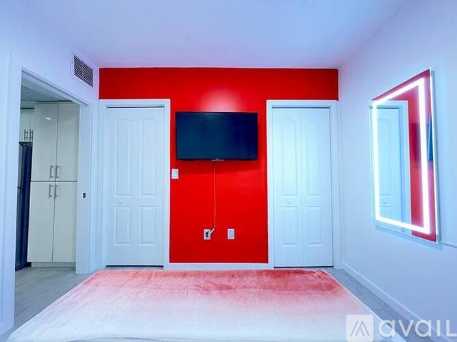 A room with a red wall and a flat screen TV mounted on it.