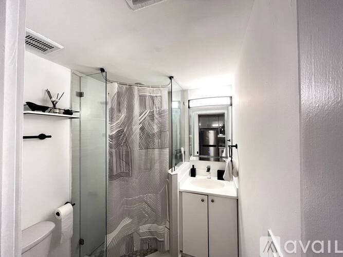 A bathroom with a glass shower door and a white cabinet.