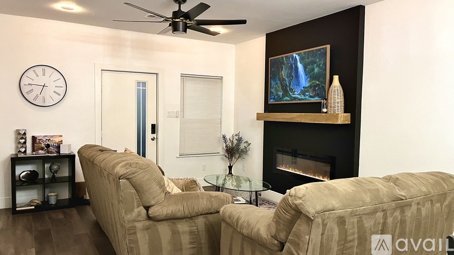 A spacious living room with a fireplace and a ceiling fan.