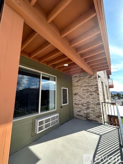 A balcony with a wooden ceiling and a brick wall.