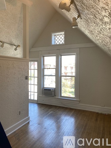 A room with a window and a wooden floor.