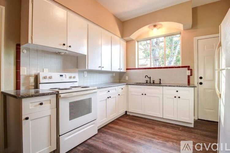 A kitchen with white cabinets and a wooden floor.
