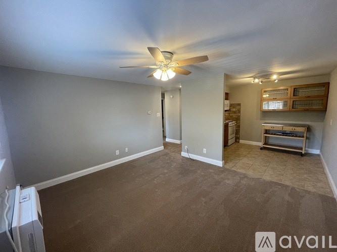 A room with a ceiling fan and a door leading to another room.