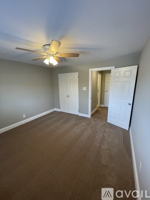 A room with a ceiling fan and carpeted floor.