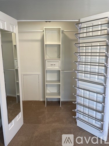 A white shelving unit with glass doors is in a room with white walls.