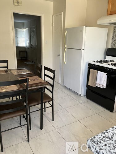 A kitchen with a table and chairs and a fridge.
