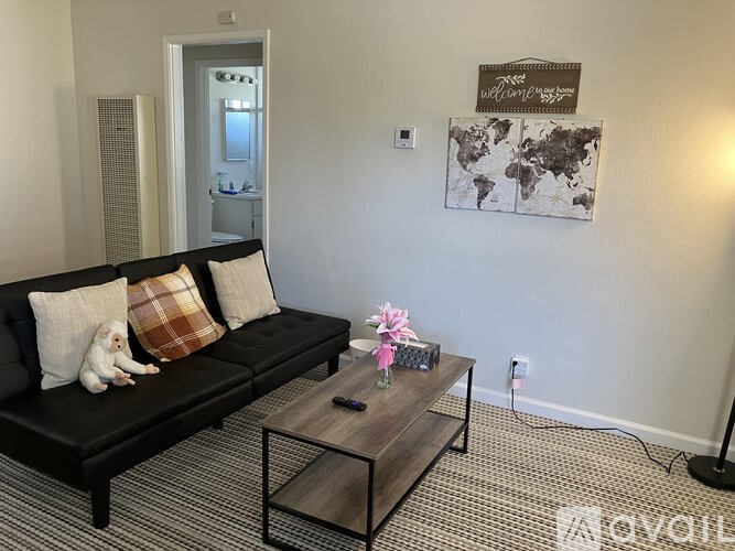 A living room with a black couch and a coffee table.