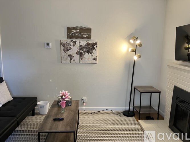 A living room with a black couch, a wooden coffee table, a world map on the wall, and a floor lamp.