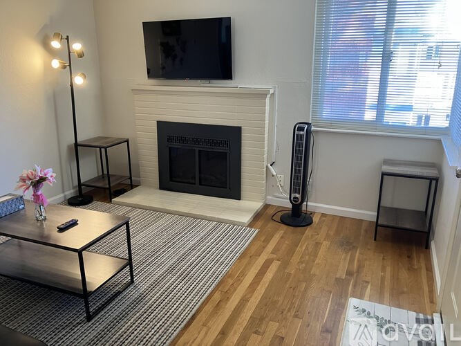 A living room with a fireplace and a flat screen TV mounted above it.