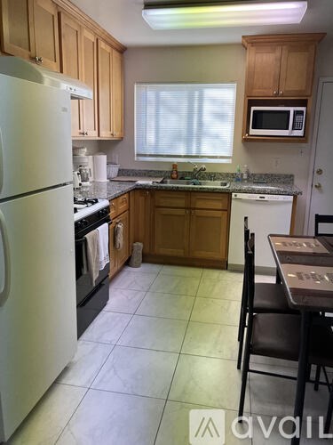 A kitchen with a white refrigerator, wooden cabinets, and a black dining table.