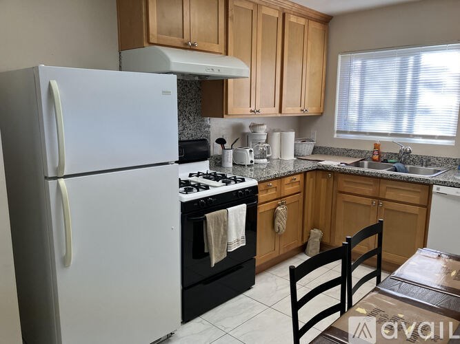 A kitchen with a white fridge, black stove and wooden cabinets.