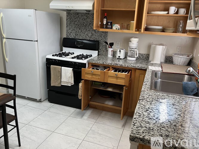 A kitchen with a white fridge, black stove, and wooden cabinets.