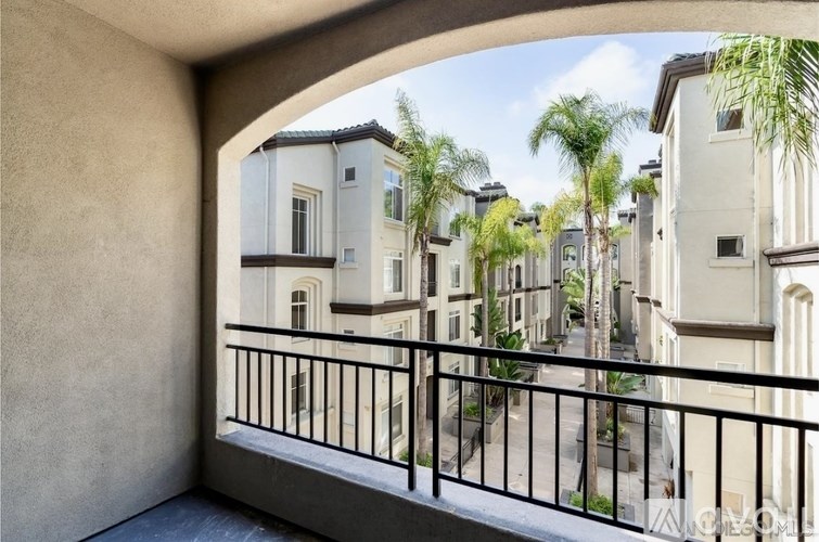 A balcony overlooks a row of houses and palm trees.