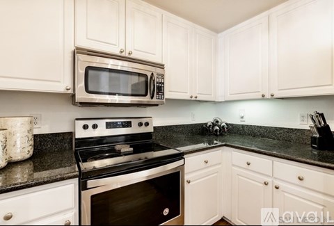 A kitchen with white cabinets and black countertops.