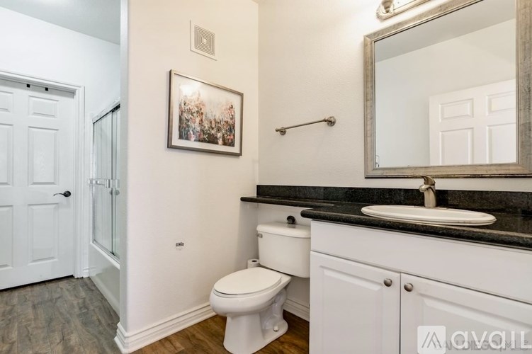 A bathroom with a toilet, sink, and mirror.