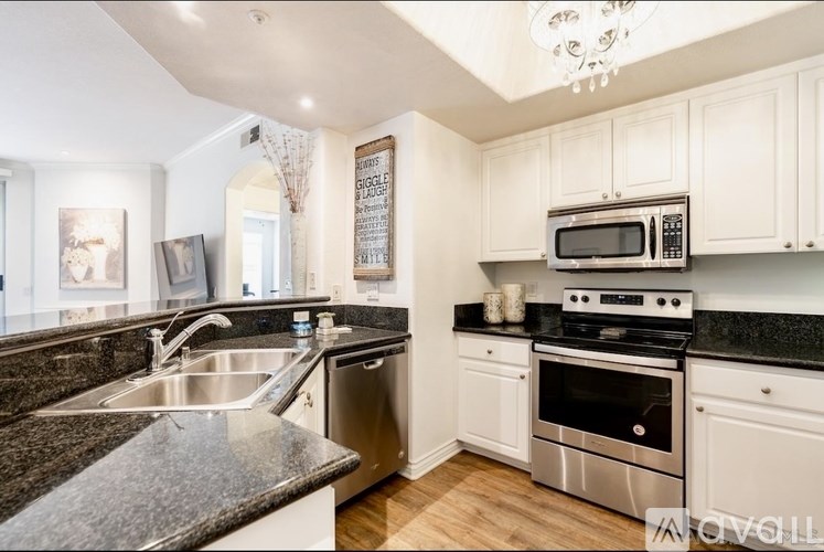 A modern kitchen with white cabinets and black countertops.
