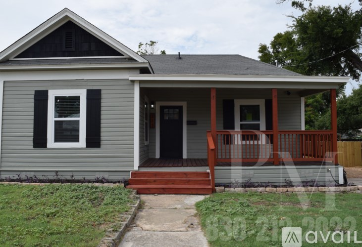 A small house with a grey front and a red porch.
