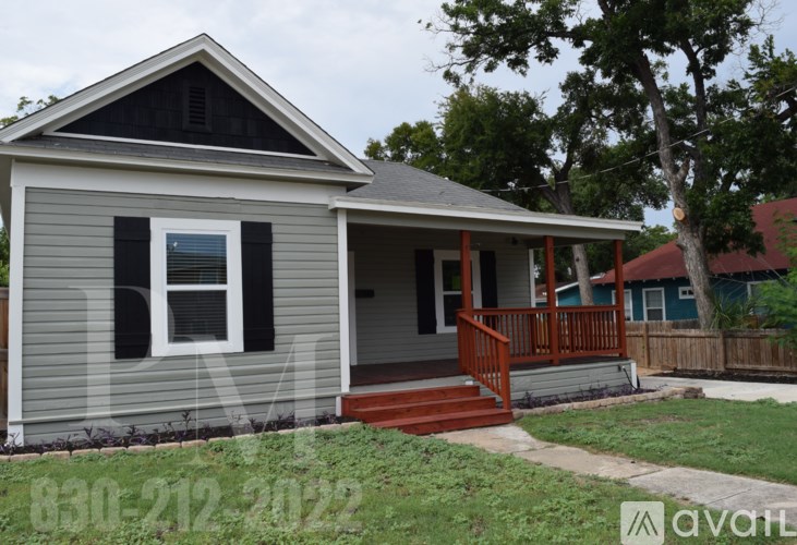 A small house with a porch and a tree in the background.