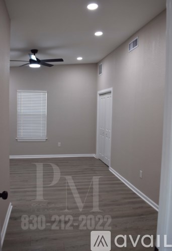 A room with a ceiling fan and a door on the right side.