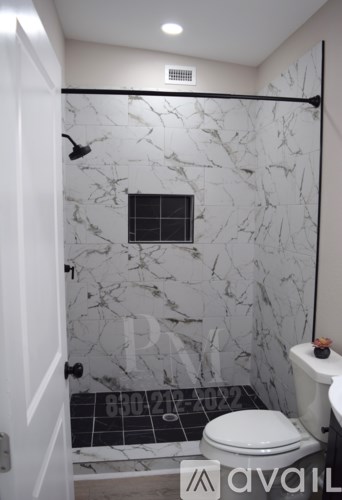A bathroom with a marble shower and toilet.