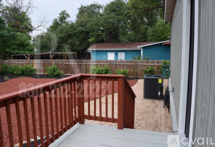 A deck with a railing and a view of a backyard with a pool and a house.