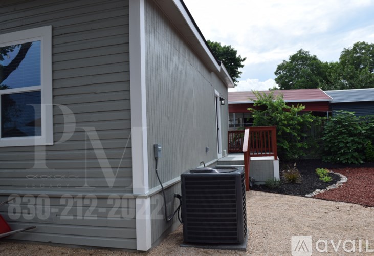 A house with a grey siding and a red roof is shown with a window, a door, and a black air conditioning unit.