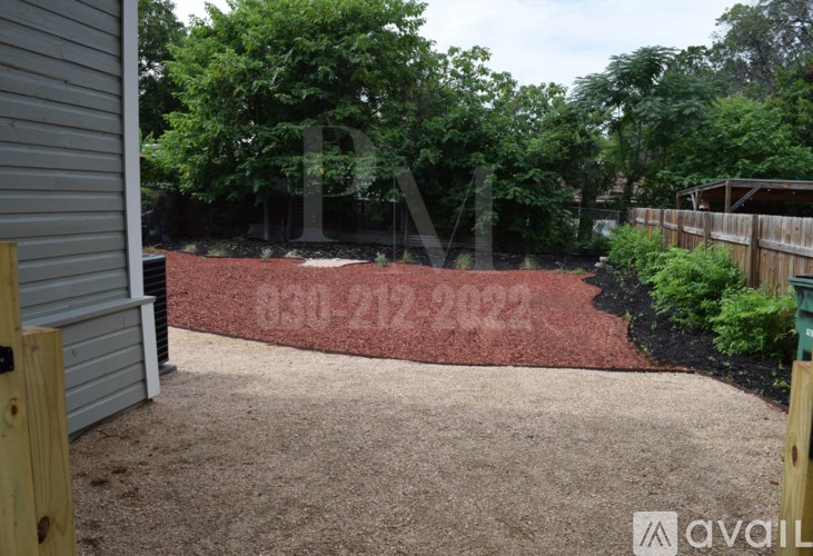 A backyard with a red mulch area and a wooden fence.