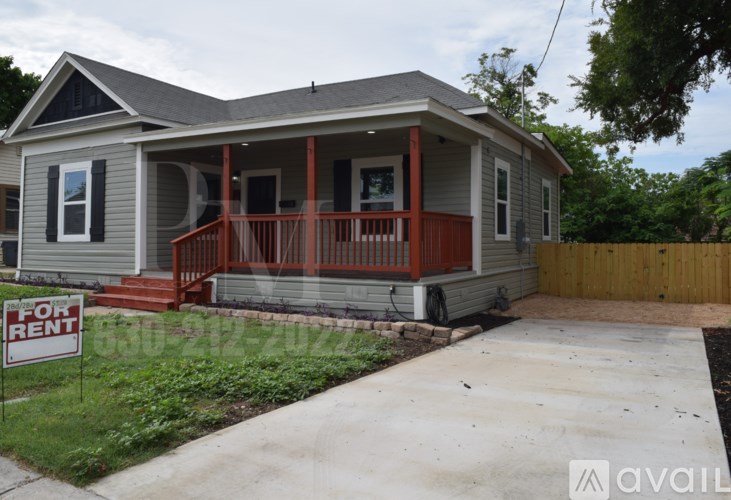 A house with a porch and a "For Rent" sign in front.
