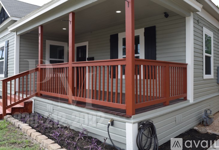 A house with a grey siding and a red railing on the porch.