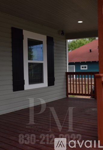 A porch with a window and a view of a green house.