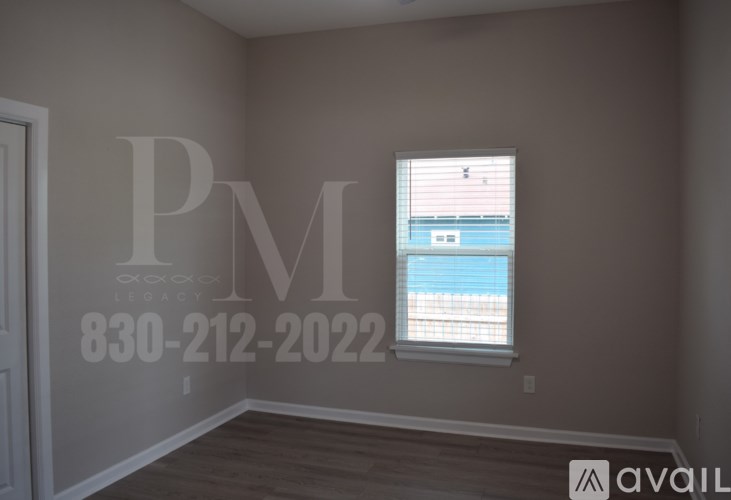 A room with a window showing a blue sky and a wall with a large letter PM and a phone number.