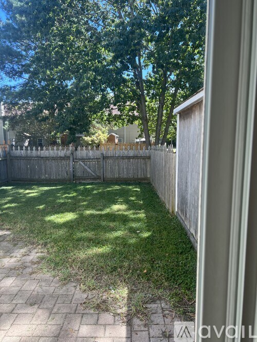 A backyard with a wooden fence and a brick pathway.